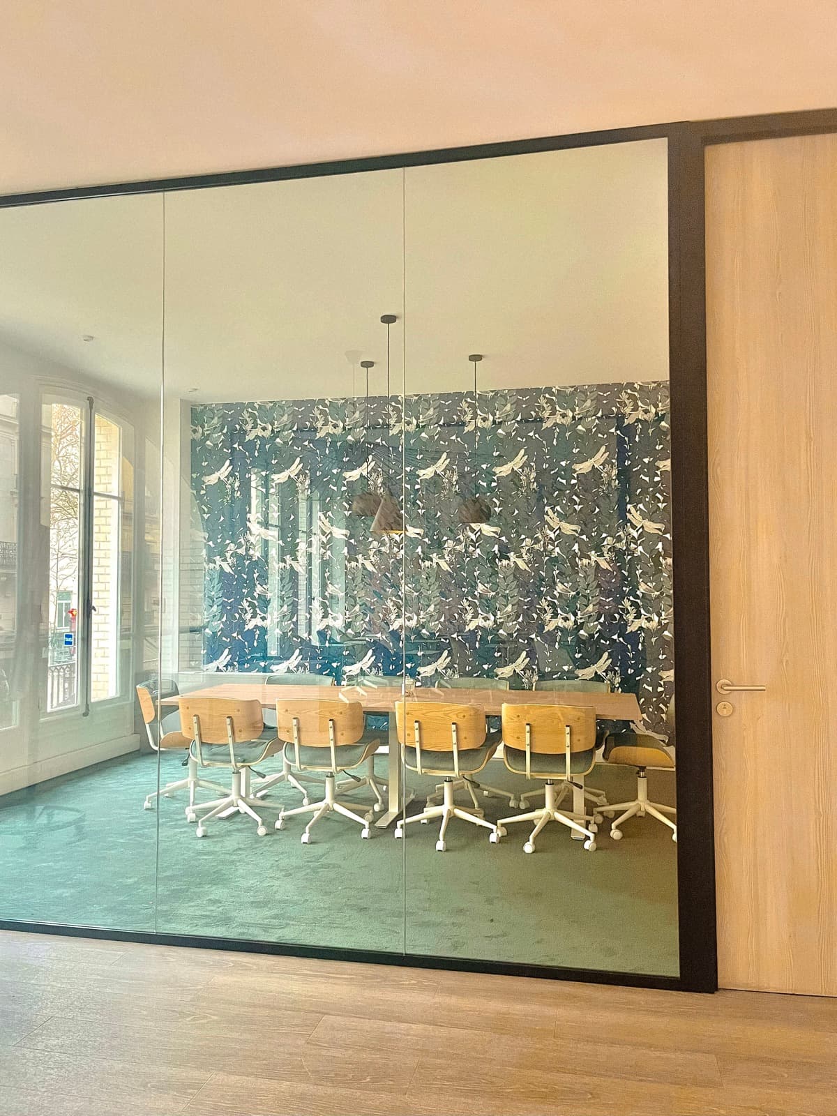 Salle vitrée en configuration board room avec table longue et chaises roulantes