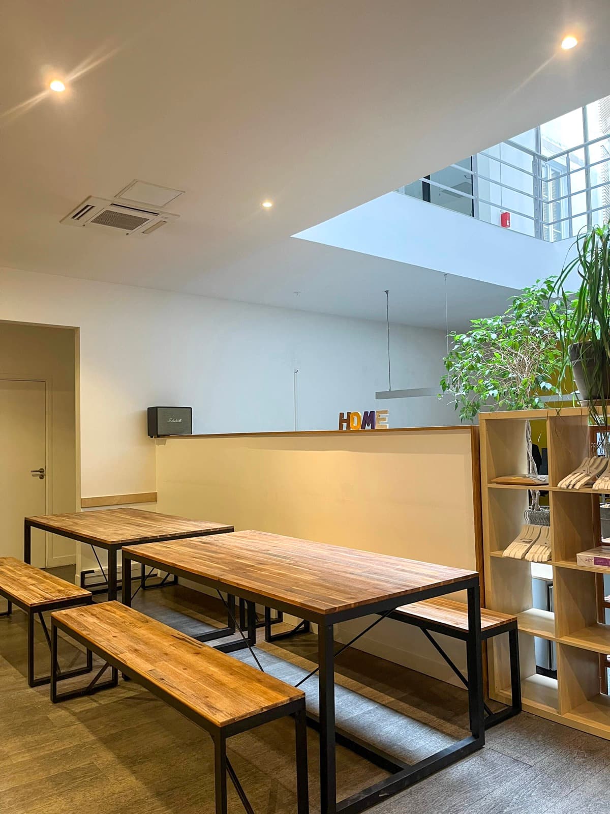 Espace repas avec longues tables bois et bancs sous verrière